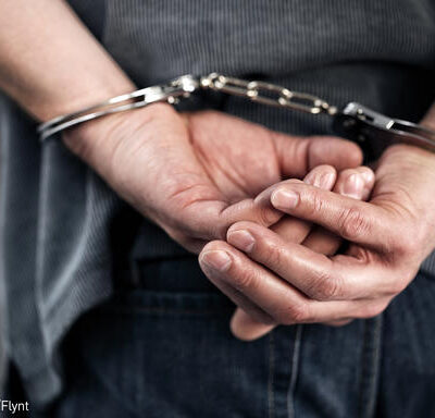 An image of a man with hands handcuffed behind his back