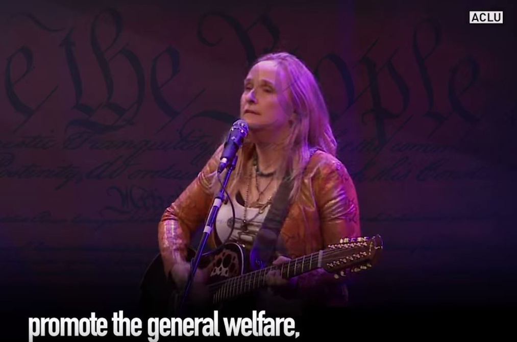 woman playing guitar with the words promote the general welfare