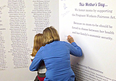 A mother and child sign the 'Largest Mother's Day Card Ever to Hit Capitol Hill'