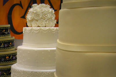 two 3-tier white wedding cakes, one with white flowers on top