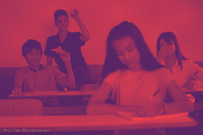 Boys in a classroom throwing paper airplanes at a female student sitting in front of them