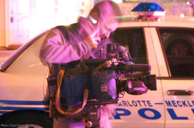 Reporter in front of police car at police activity scene
