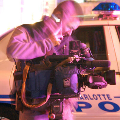 Reporter in front of police car at police activity scene