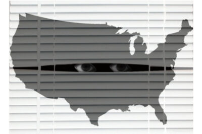 A pair of eyes looks through a break of venetian blinds while an transparent grey image of the US is in the foreground.