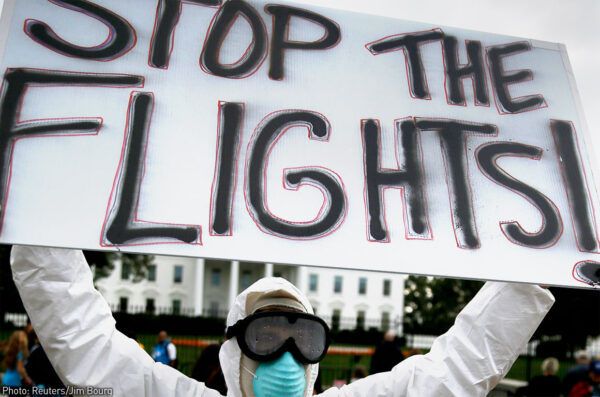 Protester holding "Stop the Flights!" sign