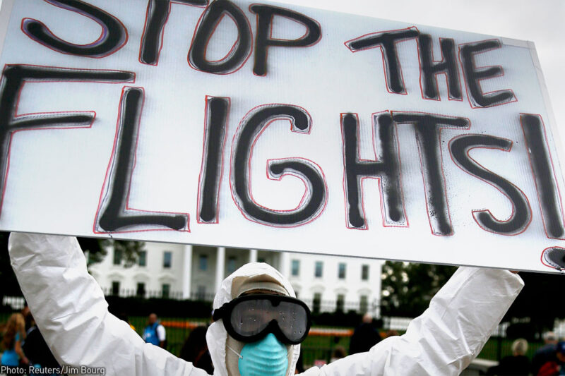 Protester holding "Stop the Flights!" sign