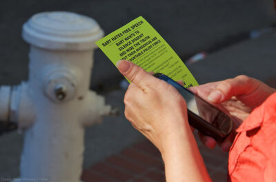Person holding cell phone and flyer