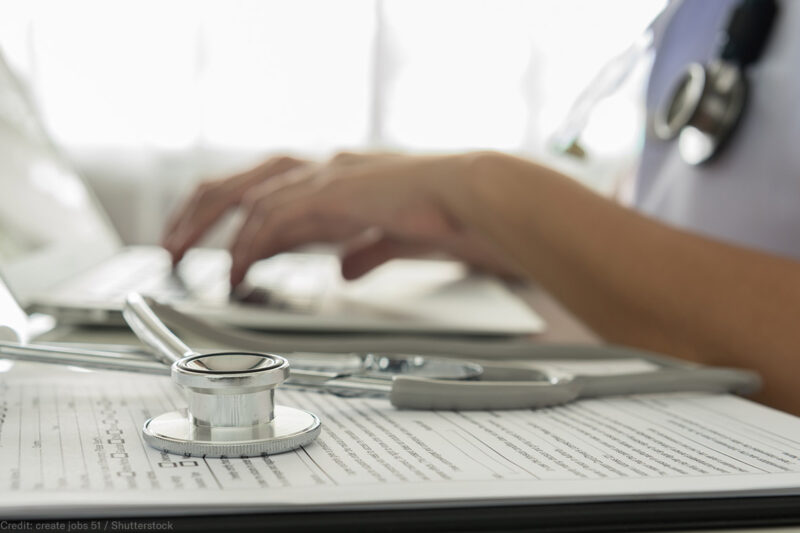 A doctor typing on a laptop computer
