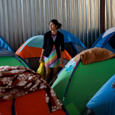 A woman from Guatemala stands surrounded by tents, in a shelter of mostly Mexican and Central American migrants waiting in the midst of the asylum application process. This comes on the heels of an unprecedented change in the US asylum process, known as the "Return to Mexico" program.