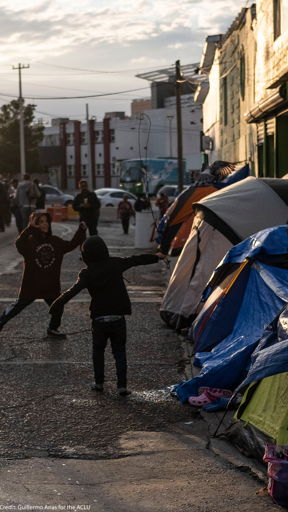Two boys running around and playing outside of tents in Ciudad Juarez, Mexico.