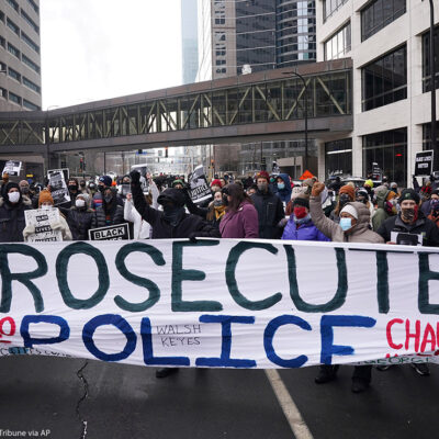 Black Lives Matter protesters stand with a banner that reads "Prosecute Police" to demand justice for Jacob Blake