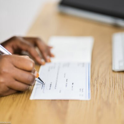 A black woman signs a cashier's cheque.