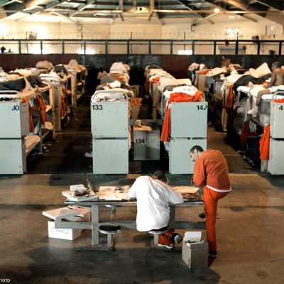 People in prison housed in a room with three-tiered bunk beds.