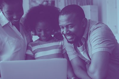 A picture of a black family smiling together as they stare at a computer, with a blue overlay on the photo.