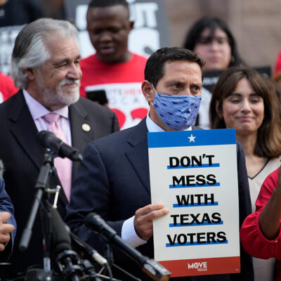 Rep. Trey Martinez Fischer, D-San Antonio, holds a sign that says, "Don't mess with Texas," as he and other Democratic caucus members join a rally on the steps of the Texas Capitol to support voting rights