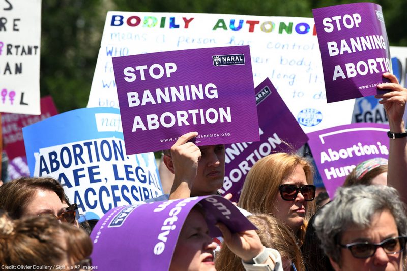 Pro-abortion activists hold placards that read "Stop Banning Abortion" during a rally at the Supreme Court