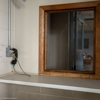 Phone next to window used by visitors to prison to communicate with inmates behind glass.