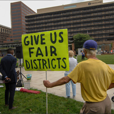 Man holding sign that says, "Give us fair districts."