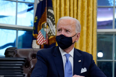 A photo of President Biden in the Oval Office wearing a mask.