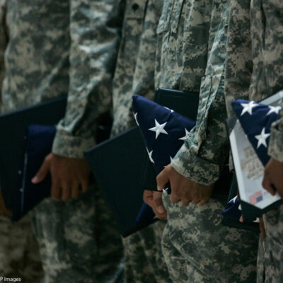 U.S. Army soldiers holding certificates and folded U.S. flags during a ceremony.