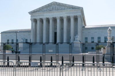 A view front of the U.S. Supreme Court Building behind riot gates.