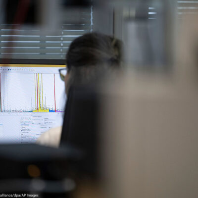 The back of a woman who is working on a laptop.