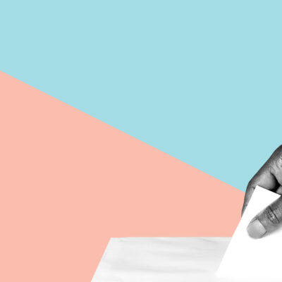 A hand putting a ballot into a ballot box.