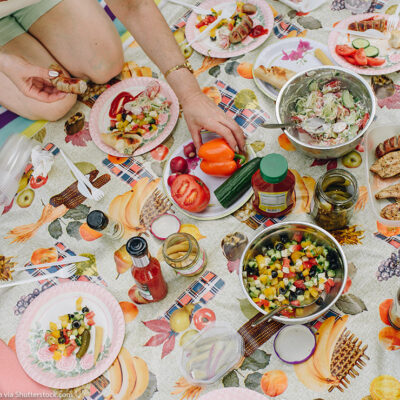 The top view of a picnic outside, with people eating various prepared foods.