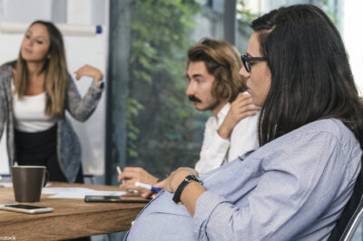 A seated pregnant woman participating in a brainstorming meeting.