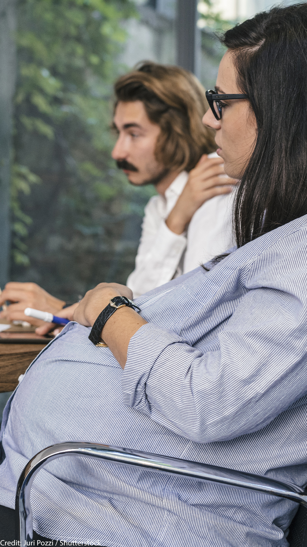 A seated pregnant woman participating in a brainstorming meeting.