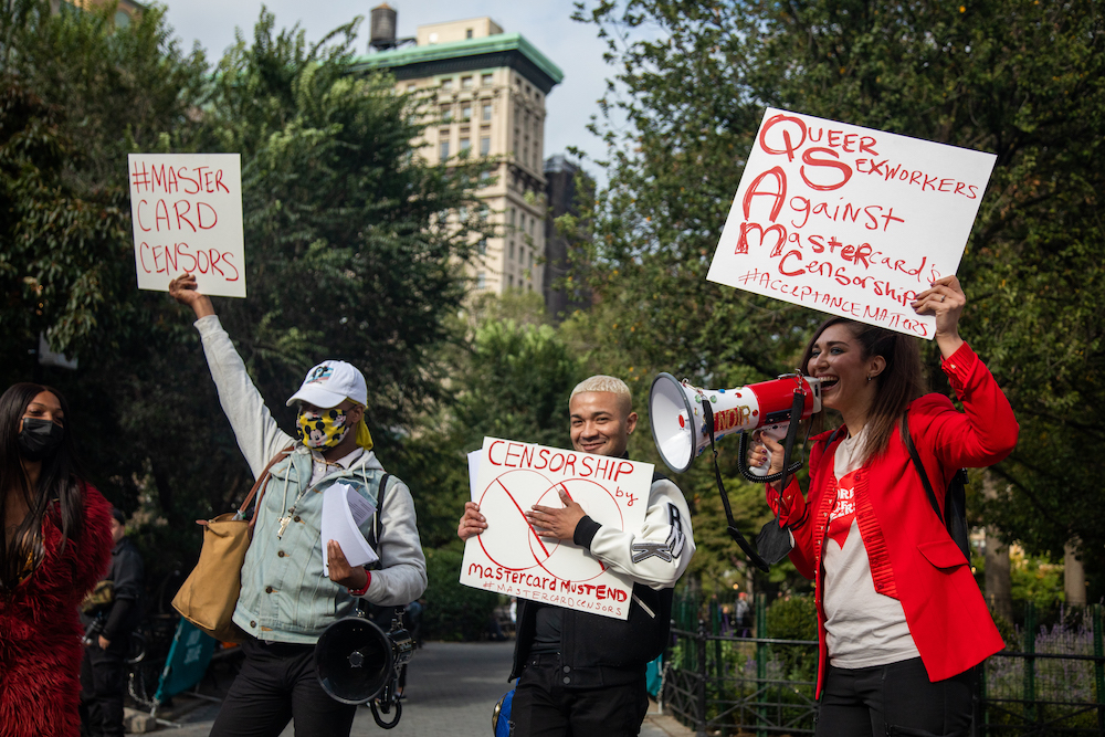 Protestors holding signs against Mastercard's policies that can harm sex workers.