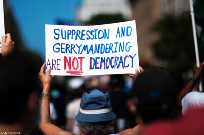 A demonstrator at the March On for Voting Rights in Washington D.C. holds up a sign reading "Suppression and Gerrymandering are Not Democracy".