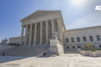 The U.S. Supreme Court building on a sunny day with a blue sky.