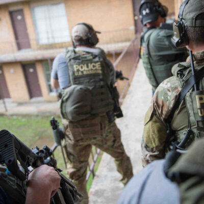 An image of 5 people holding police gear.