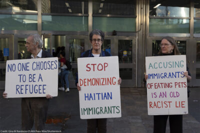 Anti-demonization of immigrants demonstrators hold signs that reads 'NO ONE CHOOSES TO BE A REFUGEE' 'STOP DEMONIZING HAITIAN IMMIGRANTS' 'ACCUSING IMMIGRANTS OF EATING PETS IS AN OLD RACIST LIE.