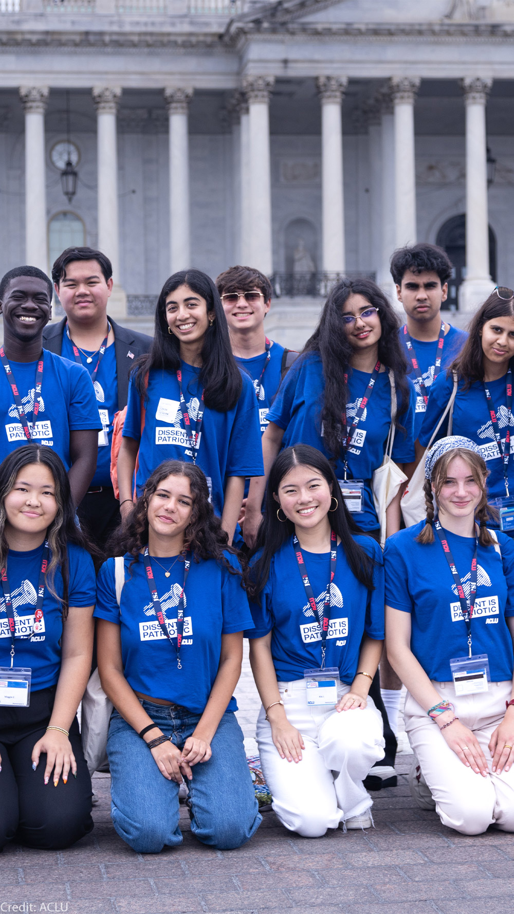A group of high school students wearing blue shirts reading "DISSENT IS PATRIOTIC" pose for the camera.