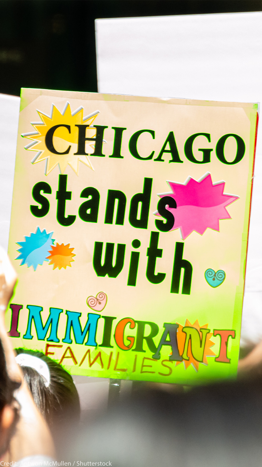 A demonstrator holds a sign that reads "Chicago Stands With Immigrant Families".