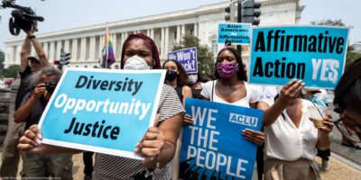 Protesters in front of the Supreme Court hold signs that read, "Diversity, Opportunity, Justice", "ACLU, WE THE PEOPLE", "Affirmative Action YES!" and "Asians for Affirmative Action".