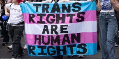Trans Rights, speakers, protesters, and supporters denounce the Trump Administration's persistent attacks on the transgender community. by carrying a huge sign reading" TRANS RIGHTS ARE HUMAN RIGHTS".