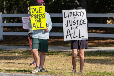 A protest with individuals holding signs in favor of due process.