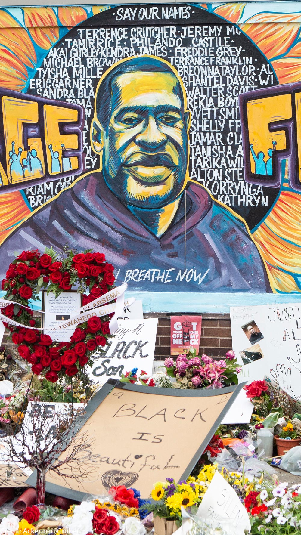 A mural with the image of George Floyd ihas flowers and signs protesting his murder lay beneath it five years later.