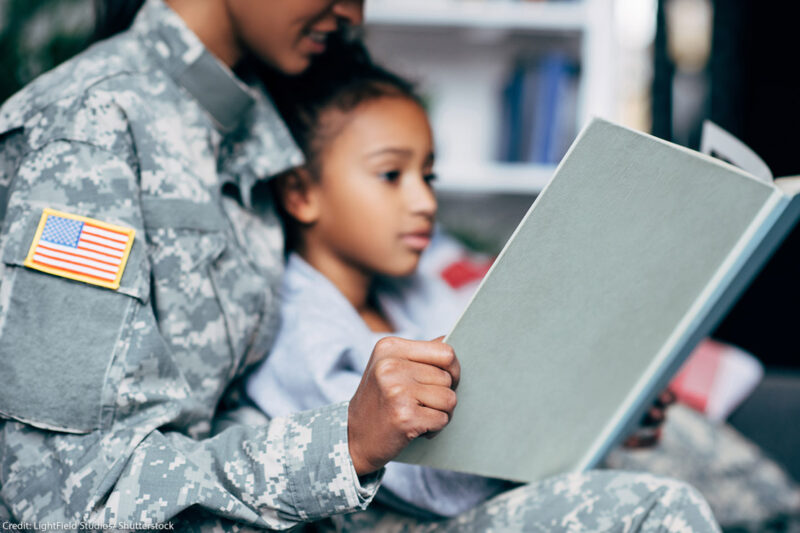 A mother in a military uniform reading to her daughter.
