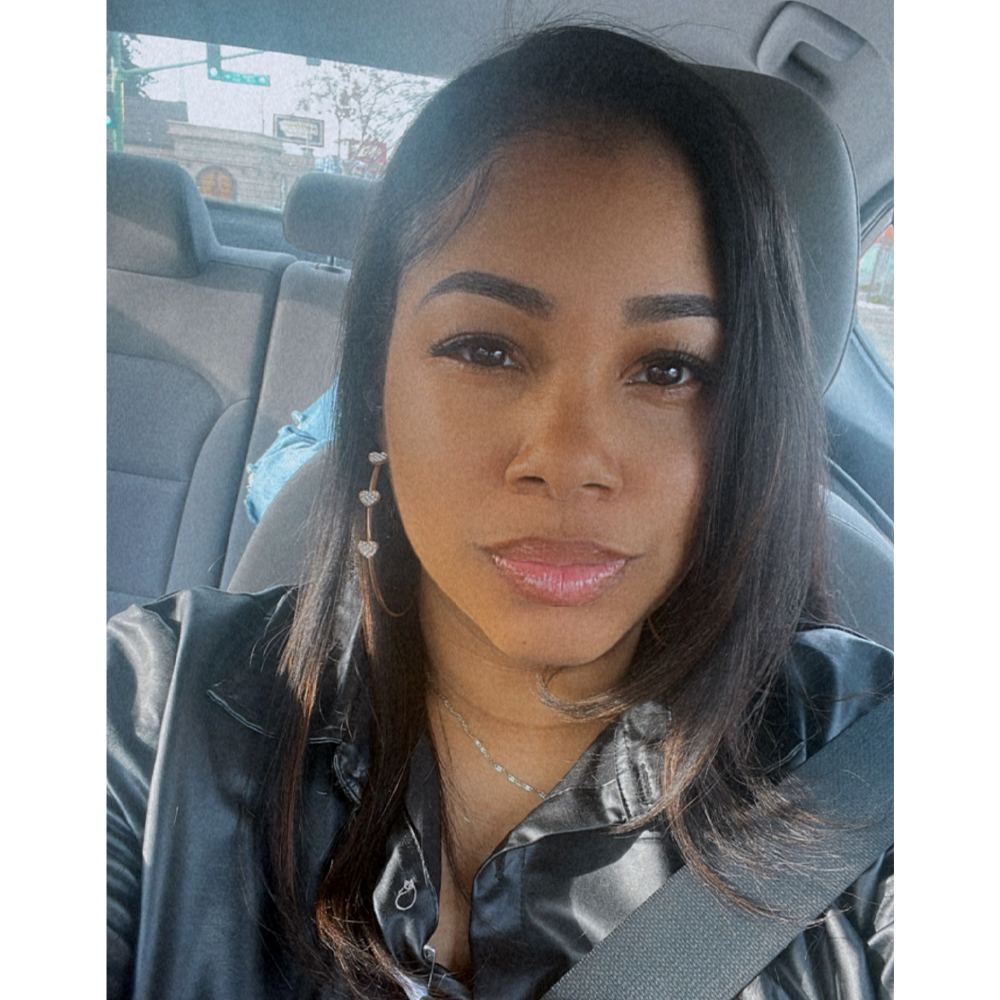 Osbornique Williams looks intently into the camera as she sits in the driver seat of her car.