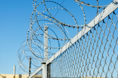 A chain link fence with razor wire running along the top.