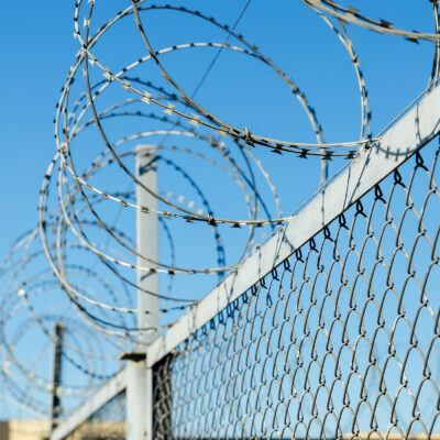 A chain link fence with razor wire running along the top.