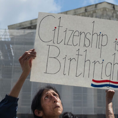A demonstrator looks up at her sign (which reads "Citizenship is a Birthright") during a rally outside the Supreme court building demanding the court uphold the 14th Amendment to the U.S. Constitution.