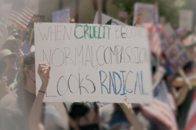 A demonstration sign that say "When Cruelty Becomes Normal, Compassion Looks Radical."