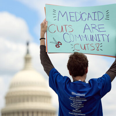 An individual at a 24-hour Vigil and Rally to Protect Medicaid on Capitol Hill, outside of the U.S. Capitol Building, holding a sign that says "Medicaid Cuts Are Community Cuts."