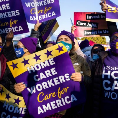 Multiple demonstrators hold up signs that read" "HOME CARE WORKERS CARE FOR AMERICA".