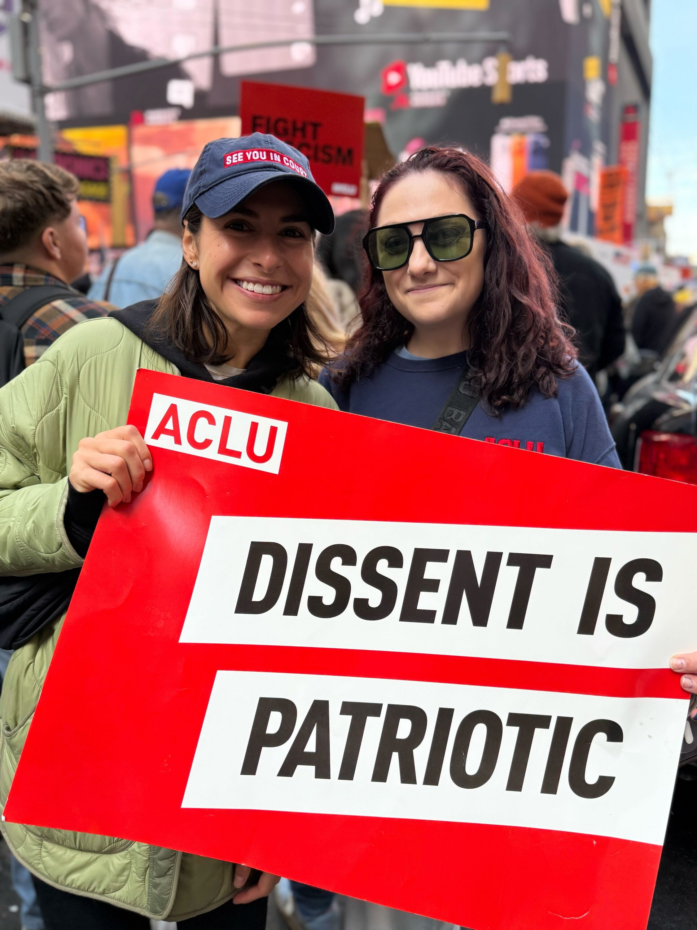 Two women hold up an ACLU placard which reads "Dissent is Patriotic"